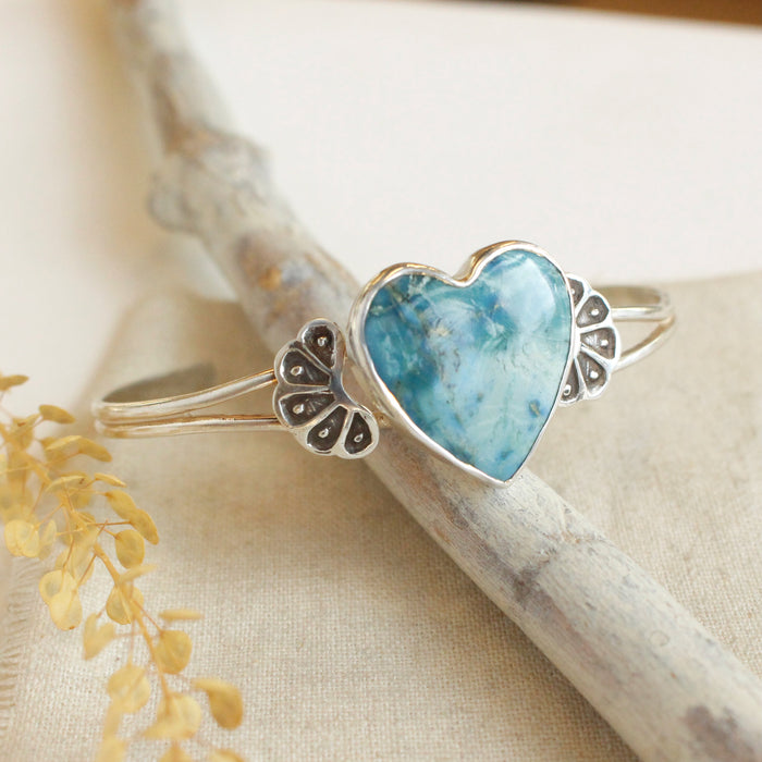 The turquoise heart cuff bracelet styled on a stick with linen and dried grass
