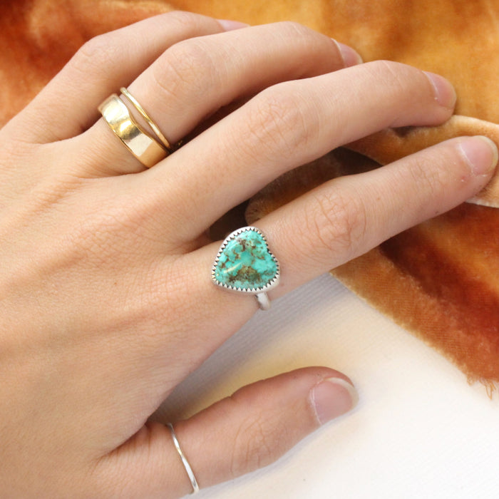 The turquoise heart ring being worn on a hand