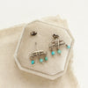 The turquoise pakal arch post earrings styled on a velvet box with linen