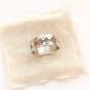 A rustic stamped silver ring styled on tan linen