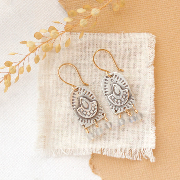The wanderer arch mixed metal labradorite earrings styled on linen with dried grass