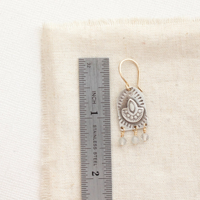 A wanderer arch mixed metal labradorite earring next to a ruler for size reference