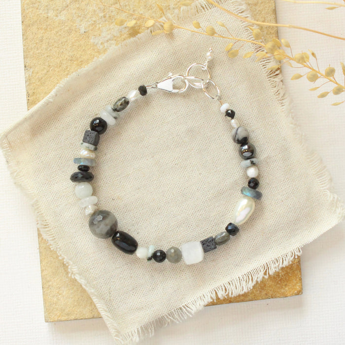 The dark side of the moon bracelet styled on a tan rock with linen and dried grass