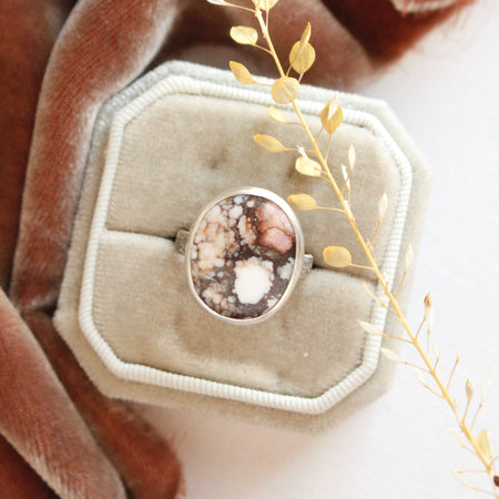 The white horse magnesite ring styled on a velvet box with brown velvet and dried grass