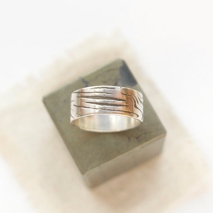 The woodgrain texture band ring styled on a stone cube