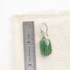 A wrapped green aventurine earring next to a ruler for size reference