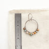 A wrapped rainbow agate hoop earring next to a ruler for size reference