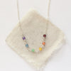 The silver wrapped rainbow necklace styled on tan linen
