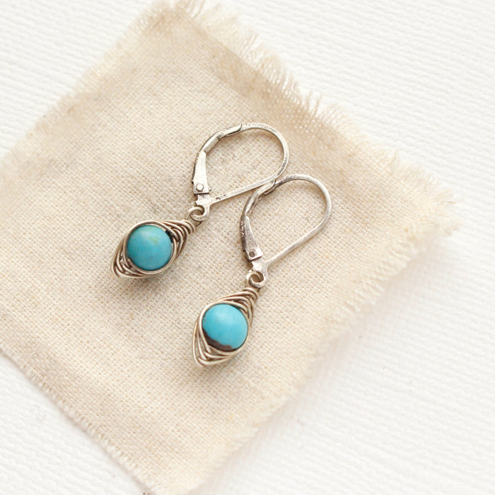 The silver wrapped turquoise earrings styled on tan linen