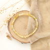 The yellow opal stretch bracelet styled on wood with tan velvet and dried grass