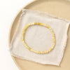 The yellow opal stretch bracelet styled on a tan plate with linen
