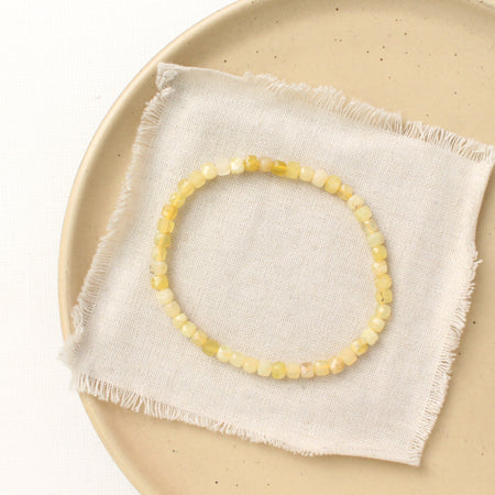 The yellow opal stretch bracelet styled on a tan plate with linen