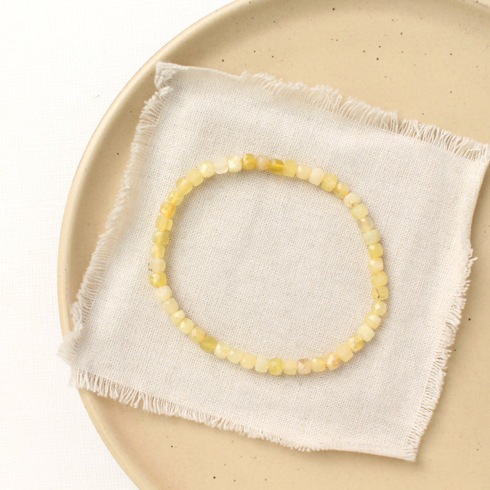 The yellow opal stretch bracelet styled on a tan plate with linen