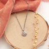 The zuni cross necklace styled on wood with orange velvet and dried grass
