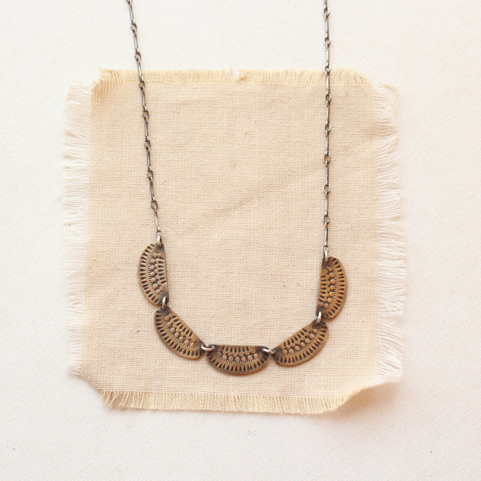 The stamped bronze and silver asmi collar necklace styled on tan linen