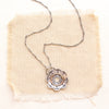 The columbine flower inspired stamped silver and 14k gold necklace styled on tan linen