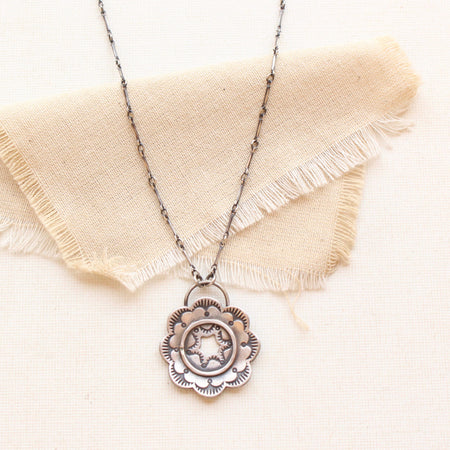 The columbine flower inspired stamped silver necklace styled on tan linen