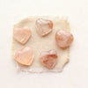 Five hematoid quartz hearts styled on tan linen.