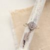 Stamped silver aspen leaf ring styled on tan linen with a wooden stick