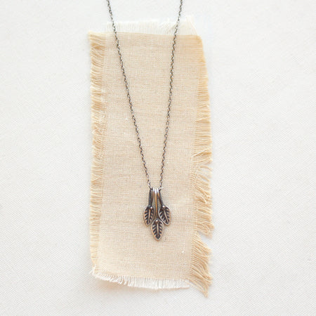 The stamped leaf trio necklace styled on tan linen