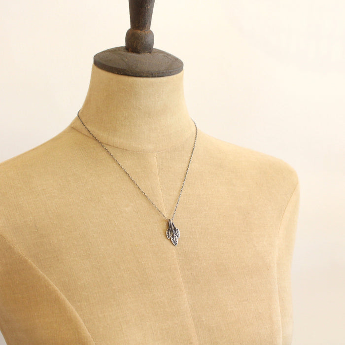 A mannequin wearing the stamped leaf trio necklace