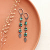 The stamped silver leaves and chrysocolla long earrings styled on a red plate with dried grass