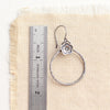 A cactus flower hoop earring next to a ruler for size reference