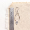 A stamped leaf teardrop hoop earring next to a ruler for size reference