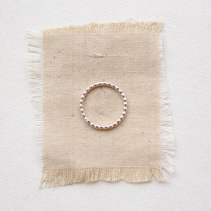 Sterling silver beaded stacking ring styled on tan linen
