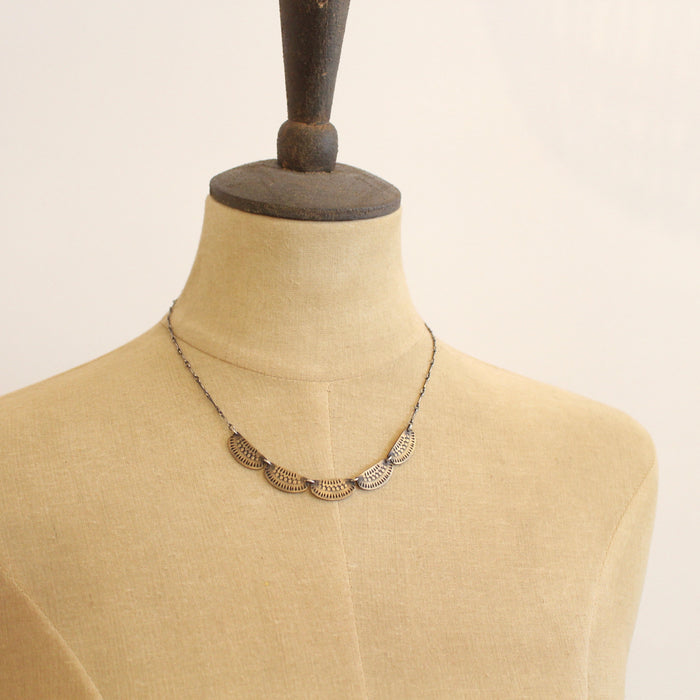 A mannequin wearing the stamped bronze and silver asmi five collar necklace