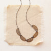 The stamped bronze and silver asmi five collar necklace styled on tan linen