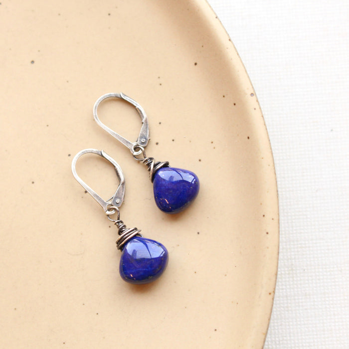 The high quality lapis drop earrings styled on a tan plate