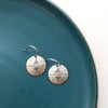 The southwest inspired pakal silver coin earrings styled on a blue plate