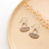 The asmi short loop mixed metal earrings styled on a tan plate with dried grass