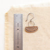An asmi short loop mixed metal earring styled next to a ruler for size reference