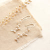 The elegant pearl wrapped silver vine earrings styled on tan linen with dried grass