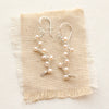 The elegant pearl wrapped silver vine earrings styled on tan linen