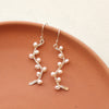 The elegant pearl wrapped silver vine earrings styled on a red plate