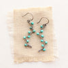 The southwest inspired turquoise wrapped silver vine earrings styled on tan linen