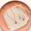 The mini talara earrings with the matching necklace styled on a red plate with tan linen and dried grass
