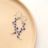 The colorful lapis wrapped silver vine earrings styled on a tan plate