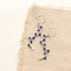 The colorful lapis wrapped silver vine earrings styled on tan linen