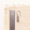 A mini sun bar earring next to a ruler for size reference
