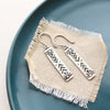 The sun bar earrings styled on a blue plate with linen