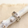 The scalloped silver ring styled on a stick and tan linen