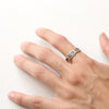 Stamped sun design on scalloped edge silver ring modeled on hand.