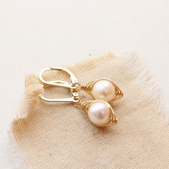 The perfect pearl gold wrapped earrings styled on tan linen