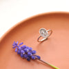 Stamped silver ring with burst design styled on a red plate with a purple flower