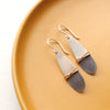 The rustic dipped teardrop mixed metal earrings styled on a yellow plate