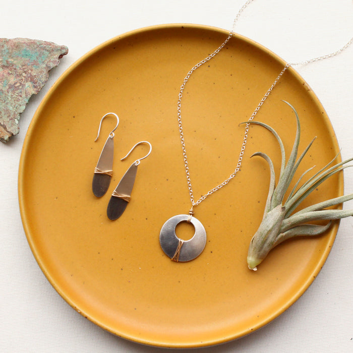 The dipped teardrop earrings with the matching necklace styled on a yellow plate with an airplant and rock